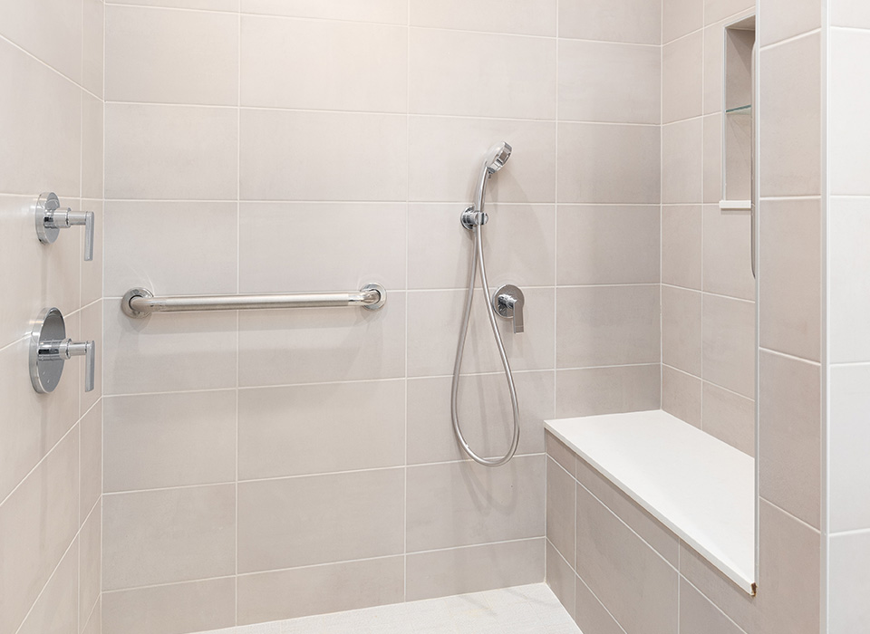 Accessible bathroom with hand held shower head and grab bars